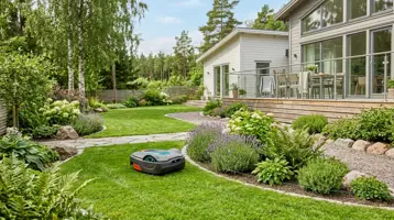 Robotgräsklippare på gräsmattan intill en perennrabatt i en svensk trädgård.