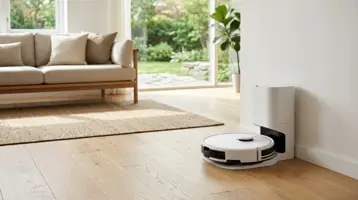 Robotdammsugare dockad i sin självtömmande basstation vid väggen.