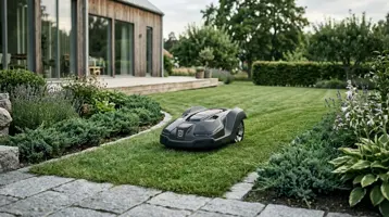 Robotgräsklippare på en välklippt gräsmatta i en stor svensk villaträdgård.