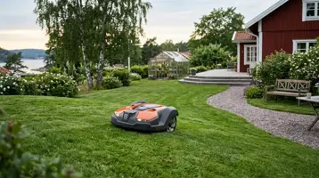 Robotgräsklippare på gräsmattan i en trädgård utan nedlagd begränsningsslinga.